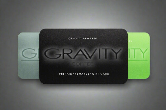 Black Gravity Rewards prepaid gift card with green and gray cards in the background